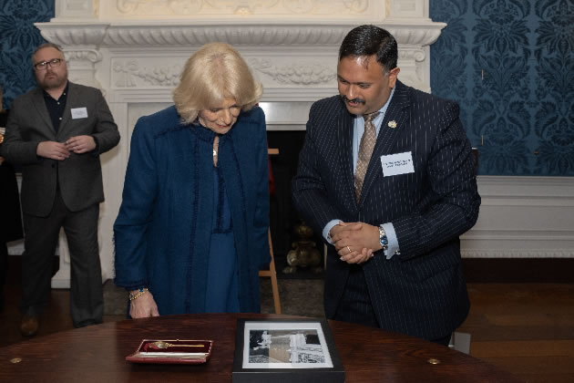 Queen Consort looking at photo of Queen Mother visiting Boston Manor House