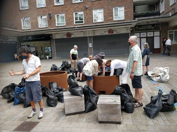 A group of people standing around a bag of luggage  Description automatically generated