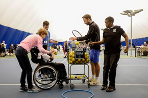 child in wheelchair helping with tennis bals at tennis festival 