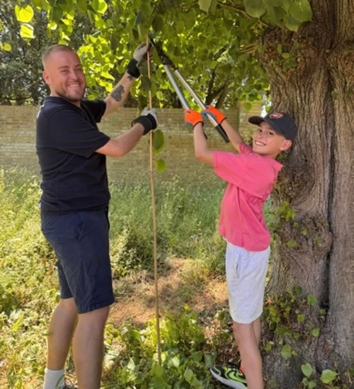 Cllr Rick Rowe pictured pruning Lime Trees with a younger volunteer during the half-term Gardening Together session